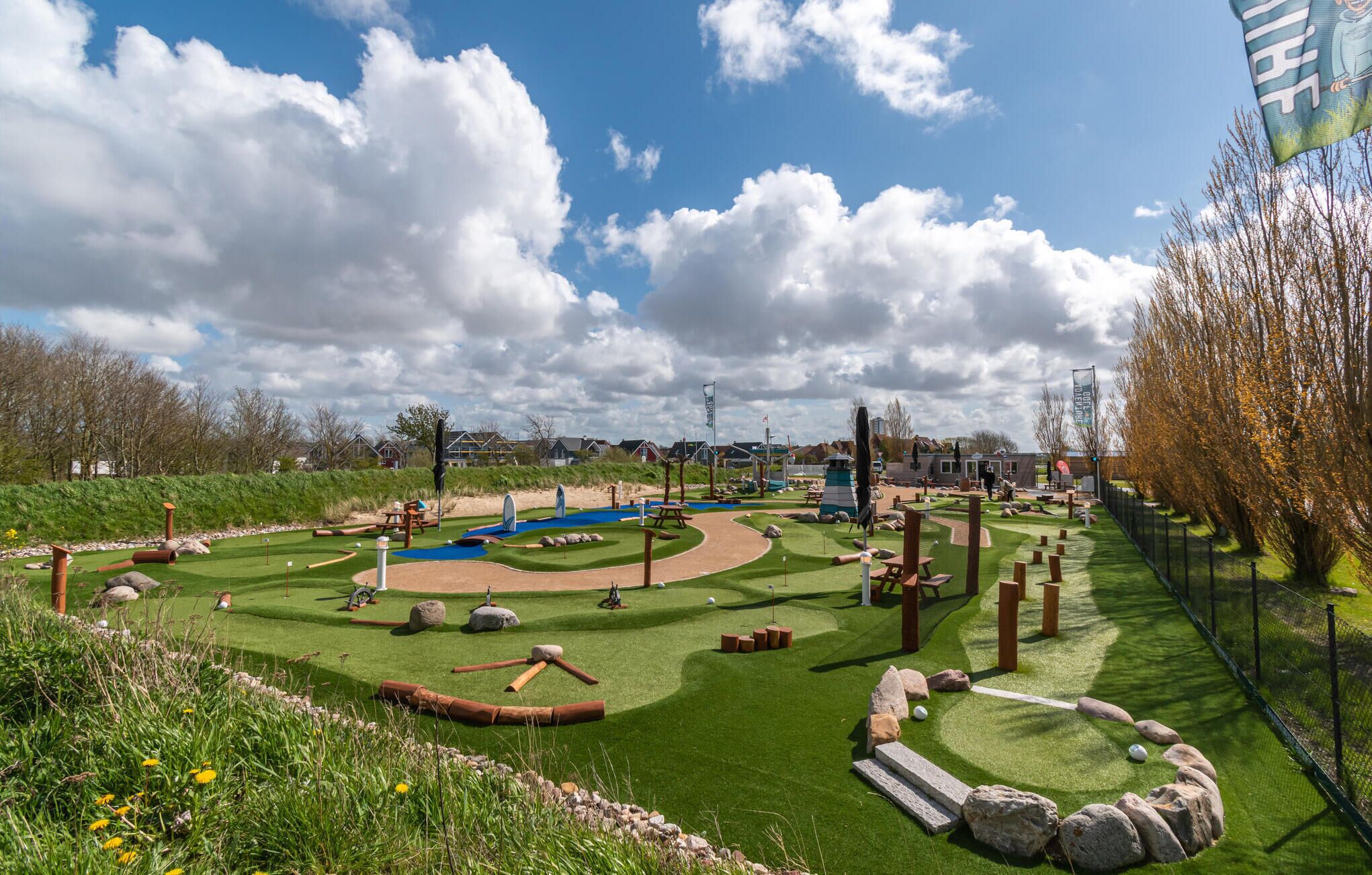 A miniature golf course with a winding path, sand traps, and various obstacles.