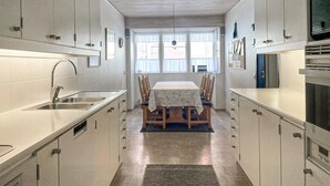 Una cocina compacta con una isla central, electrodomésticos integrados y una zona de comedor con mesa y sillas.
