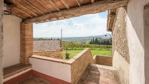 A rustic room with a tiled roof, a brick wall, and a view of vineyards and distant hills. - Awesome home in Castellina in Chianti (Castellina in Chianti)