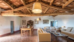 A rustic interior with exposed wooden beams, a dining area with wooden chairs, a sofa, and a coffee table. - Awesome home in Castellina in Chianti (Castellina in Chianti)