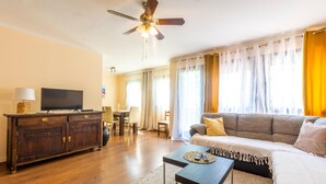 A living room with a sofa, a TV on a wooden cabinet, a ceiling fan, and a dining area with a table and chairs. - 3 bedroom lovely home in Blato na Cetini (Blato na Cetini)