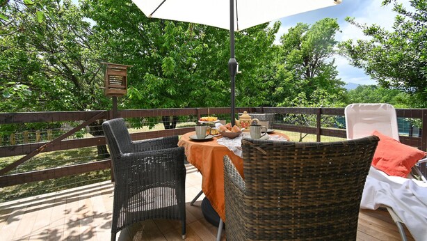 An outdoor dining area with wicker chairs, a table set with food and drinks, and a large umbrella providing shade. - 3 bedroom lovely home in Blato na Cetini (Blato na Cetini)