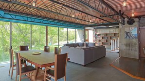 A spacious living area with a dining table and chairs, a large sofa, and a bookshelf. - Secluded 20 acre 10BR ultra contemporary retreat (Manchester-by-the-Sea)