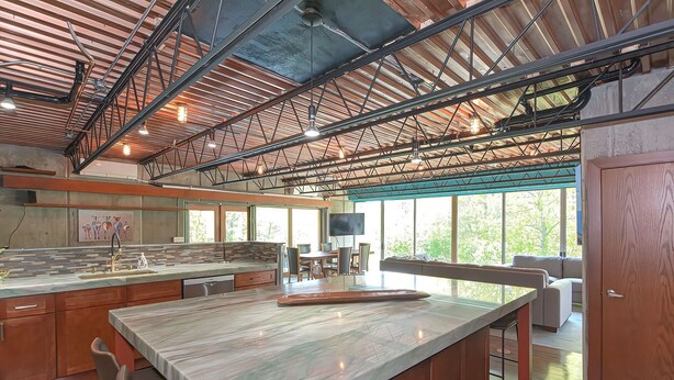 A spacious kitchen with a large island, wooden cabinets, and a high ceiling with exposed beams. - Secluded 20 acre 10BR ultra contemporary retreat (Manchester-by-the-Sea)