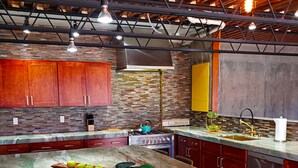 A modern kitchen with a marble countertop, wooden cabinets, and a brick backsplash. - Secluded 20 acre 10BR ultra contemporary retreat (Manchester-by-the-Sea)