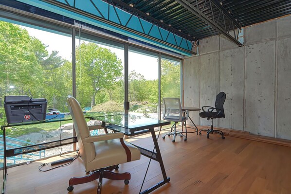 A modern office space with a large window, a desk, two chairs, and a computer.