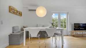 Eine moderne Küche mit einem weißen Tisch, grauen Sitzgelegenheiten und einer hängenden Leuchte.