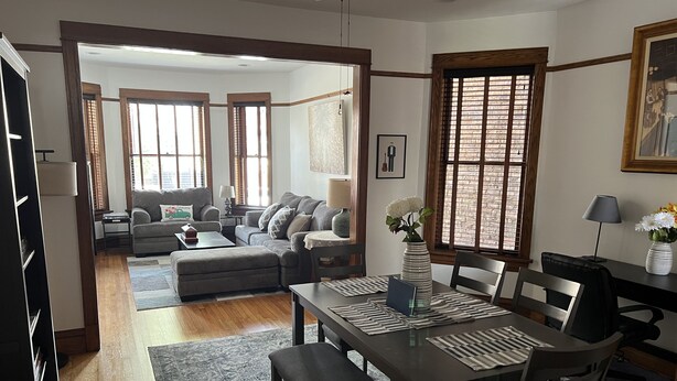 A spacious living area with a dining table, sofas, and a kitchen in the background. - Stylish, Inviting 2-BR near Logan Square and Wrigley Field (Chicago)