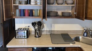 A kitchen with wooden cabinets, a Bosch dishwasher, a toaster, and various kitchen utensils. - Stylish, Inviting 2-BR near Logan Square and Wrigley Field (Chicago)