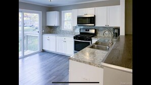 A modern kitchen with white cabinets, a stainless steel range, and a granite countertop. - Cozy modern 4 bedroom, 10 min walk to beach & sunset (Roscommon)