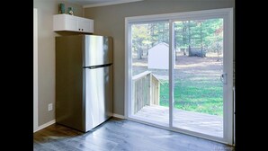 A kitchen with a stainless steel refrigerator, a wooden deck, and a sliding glass door leading to a backyard. - Cozy modern 4 bedroom, 10 min walk to beach & sunset (Roscommon)