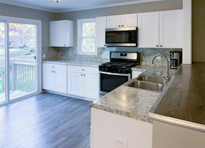 A modern kitchen with white cabinets, a stainless steel range, and a granite countertop. - Cozy modern 4 bedroom, 10 min walk to beach & sunset (Roscommon)