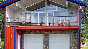 A two-story building with a red and blue exterior, a balcony with railings, and two garage doors. - Awesome apartment in Färgelanda (Färgelanda)