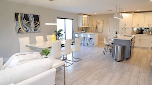 Une cuisine moderne avec des meubles blancs, un îlot central et des tabourets de bar.