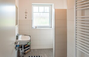 Bathroom features a sink, towel rack, and light-colored tiles.