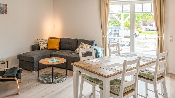 A modern living room with a grey sofa, a small round table, and a dining table with chairs. - 2 bedroom beautiful home in Stapel (Stapel)