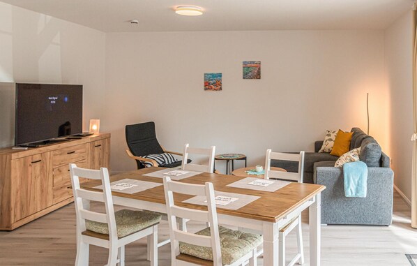 Cozy living room with a dining table, flat-screen TV, and comfortable sofa.