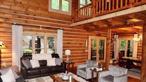 A log cabin interior with a living room featuring a sofa, armchairs, a coffee table, and a dining area with a table and chairs. - Spacious cabin w/Hot Tub , 10 minutes from downtown Blue Ridge. (Cherry Log)