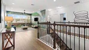 Un vaste espace de vie agrémenté d’un escalier, d’une grande fenêtre et d’une œuvre d’art moderne.