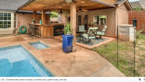 Une terrasse couverte avec une piscine, une maison d’hôtes et un bar.