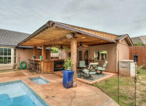 Un patio techado con piscina, una casa de huéspedes y un bar.