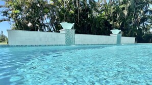 A clear swimming pool with a tiled edge and a stone wall in the background. - Luxury Island Escape @ Palm Tree Villa: Private Rooftop Deck & Saltwater Pool (Bookelia)