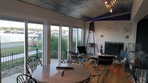 Amplia habitación con un gran ventanal con vistas a un puerto deportivo, chimenea y muebles modernos.