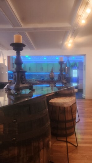 A modern kitchen with a bar area, wooden stools, and a decorative candle holder.