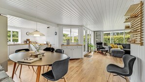 A spacious, well-lit room with a wooden floor, a round dining table, and modern furniture. - Cozy home in Ulfborg with kitchen (Ulfborg)