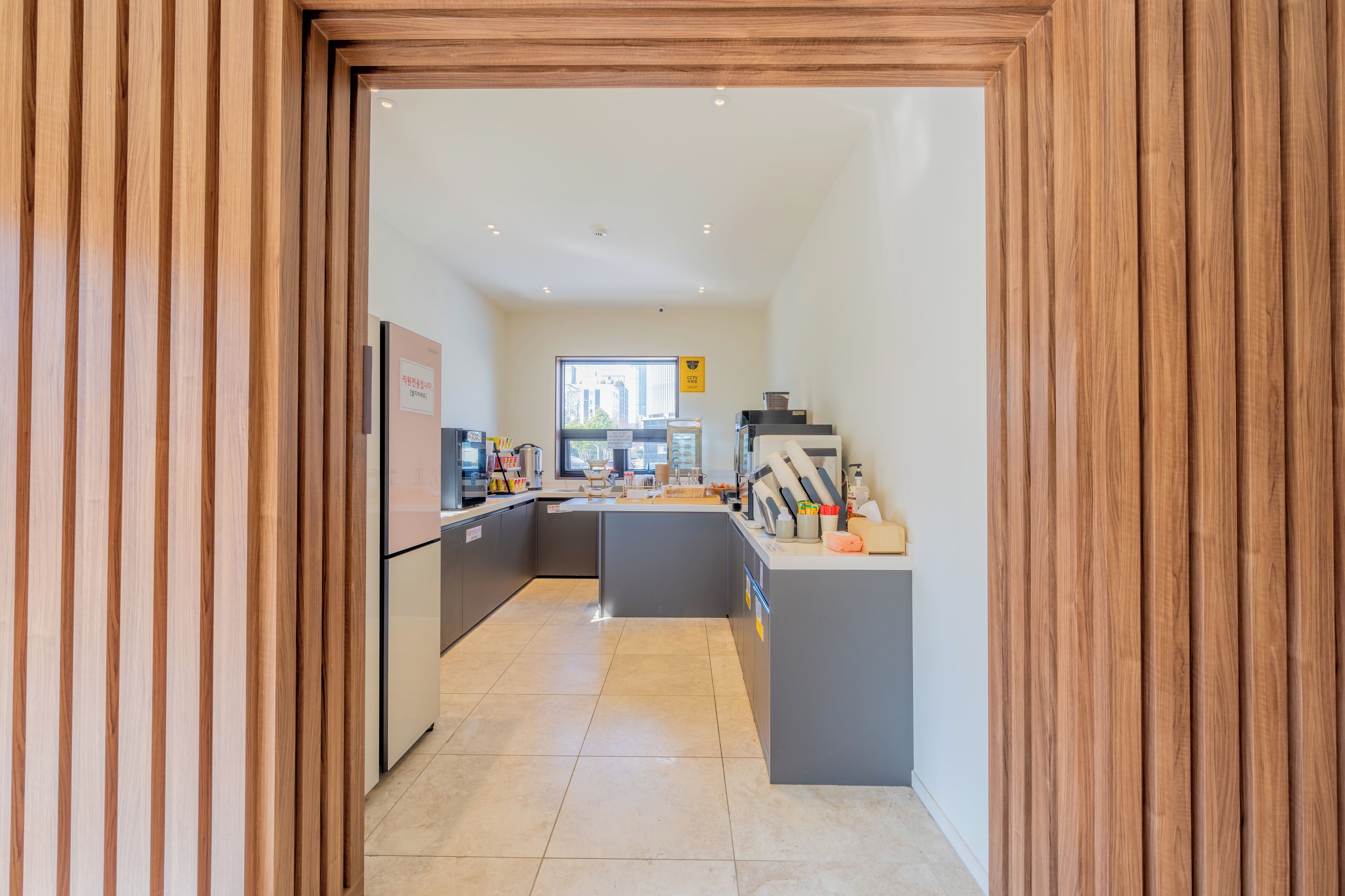 A modern kitchen with a central island, built-in appliances, and a view of the city through a large window.