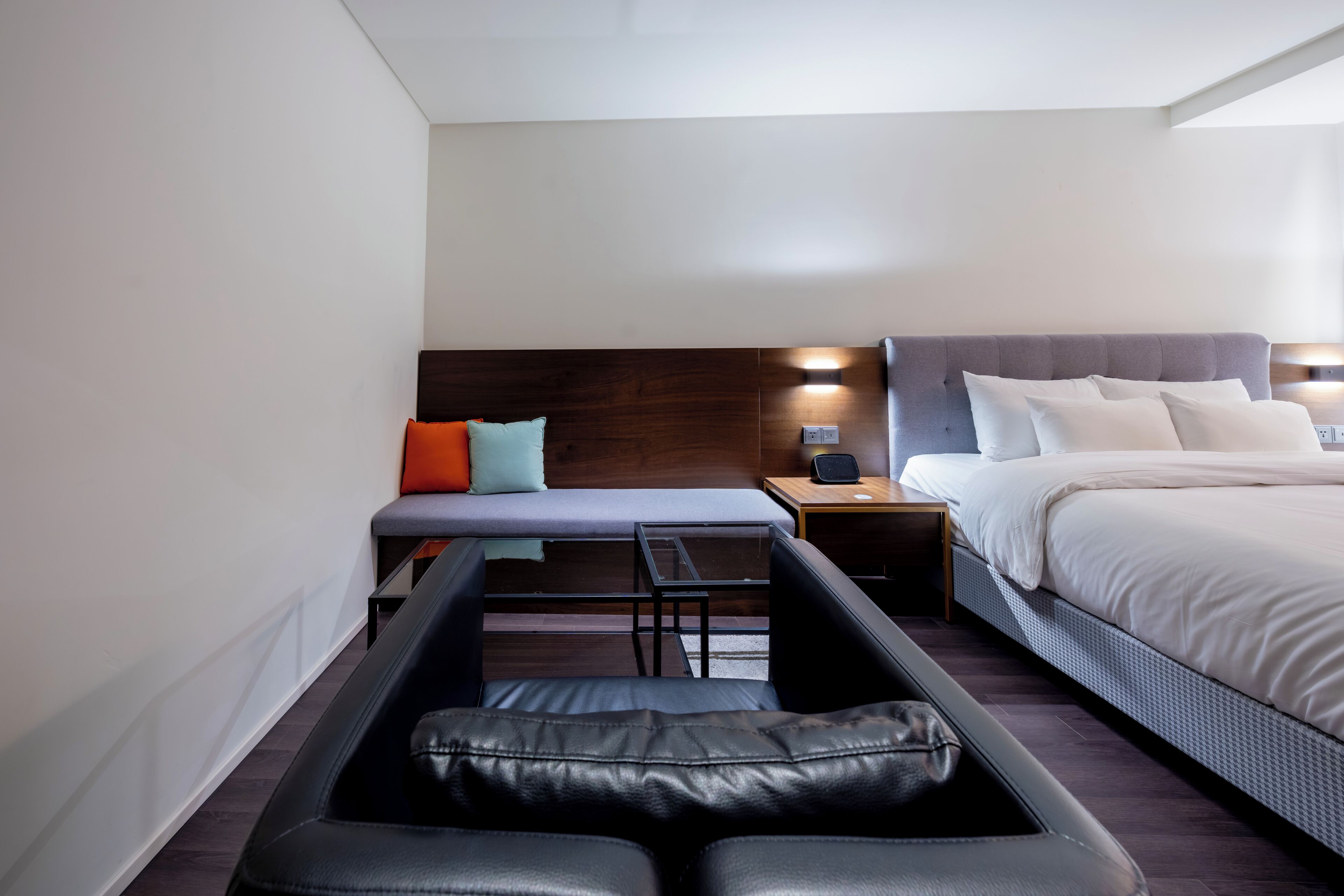 A modern hotel room with a bed, a desk, a chair, and a small table.