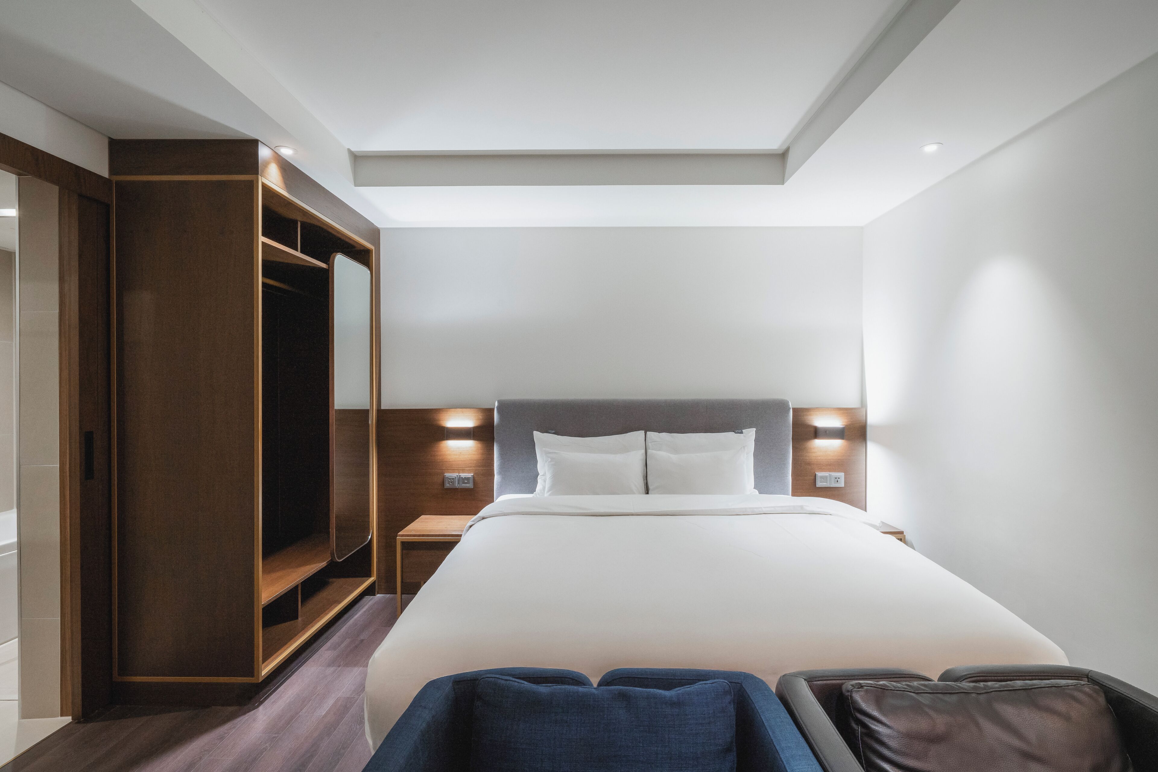 Une chambre d’hôtel moderne avec un grand lit, une armoire en bois et une lucarne.