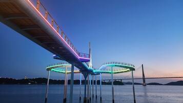 Een brug met verlichte voetpaden over water, ondersteund door pilaren.