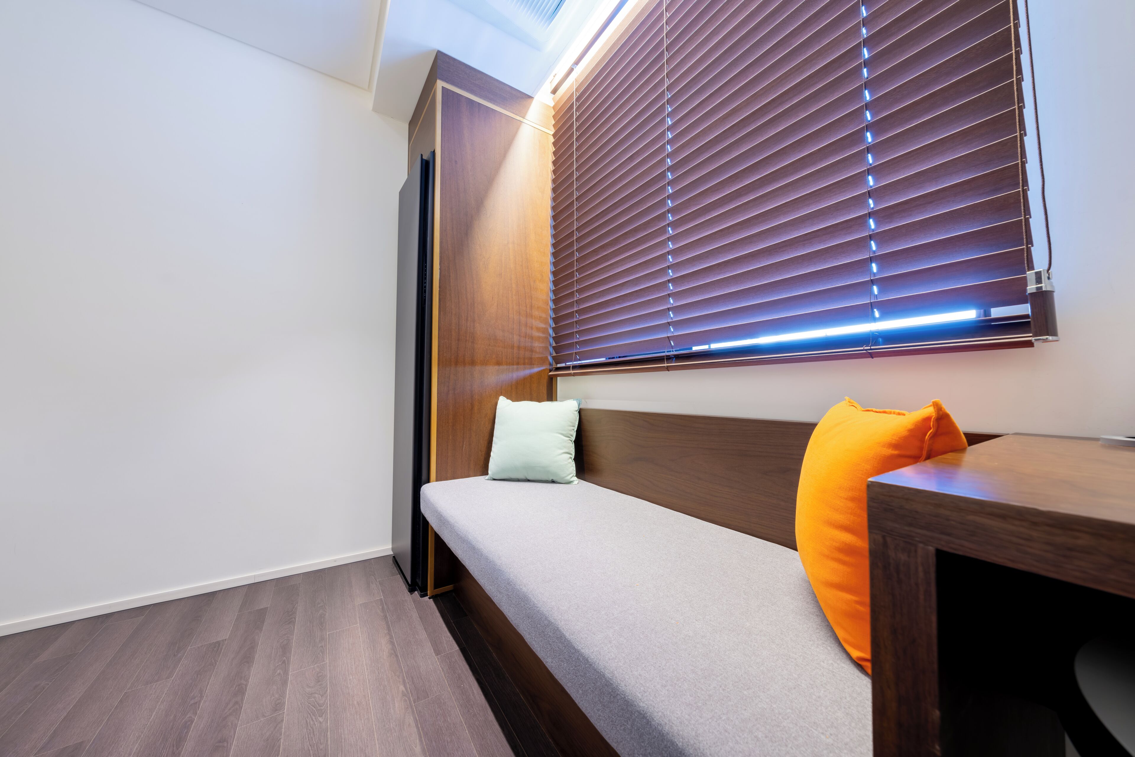 Una habitación con cama, una mesa de madera y un ventanal con persianas.