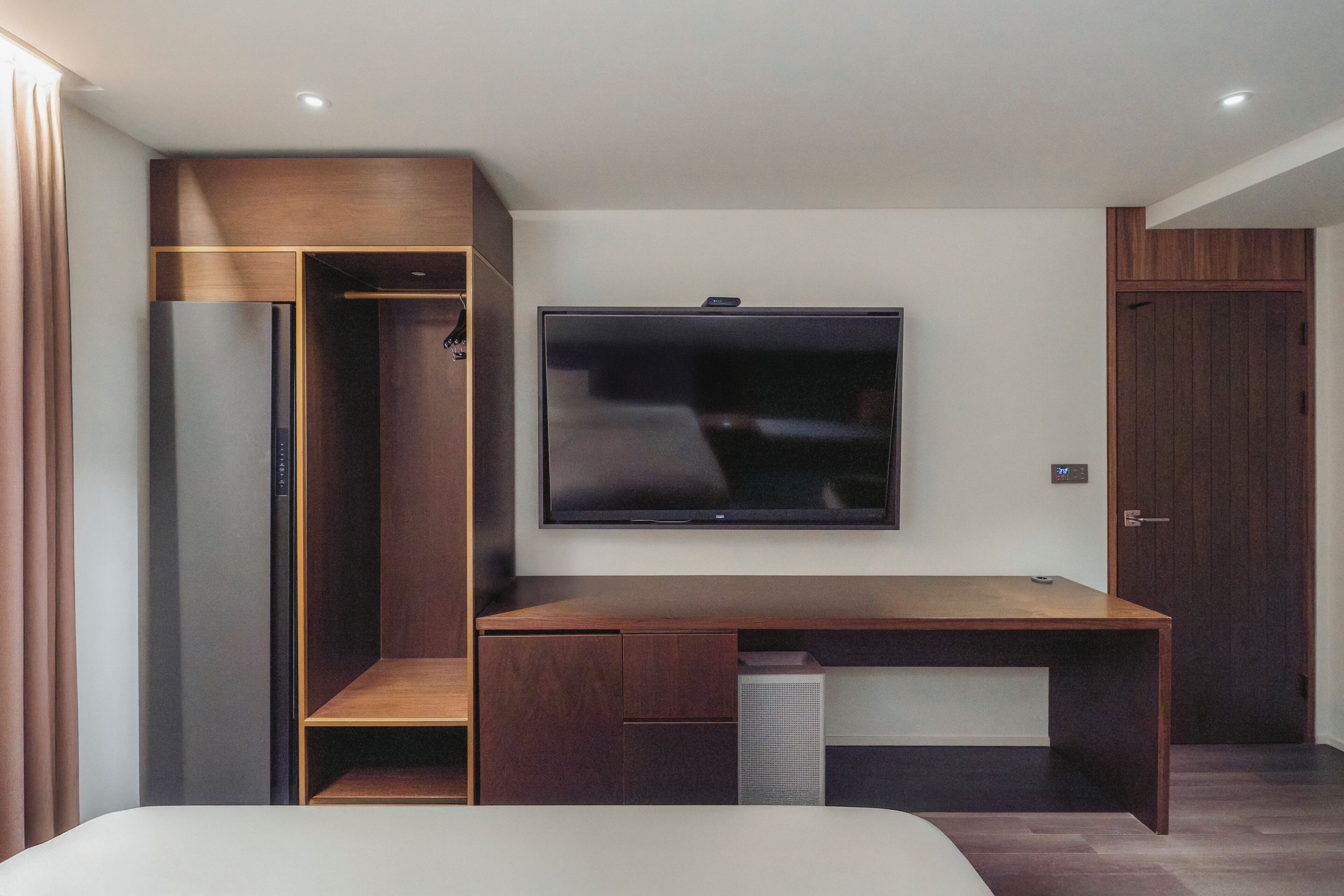 A modern bedroom with a built-in desk, a flat-screen TV, and a wardrobe.