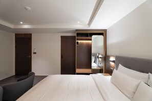 A modern hotel room with a large bed, a seating area, a wardrobe, and a mirror. - Yaja Hotel Peace Square branch (Mokpo)