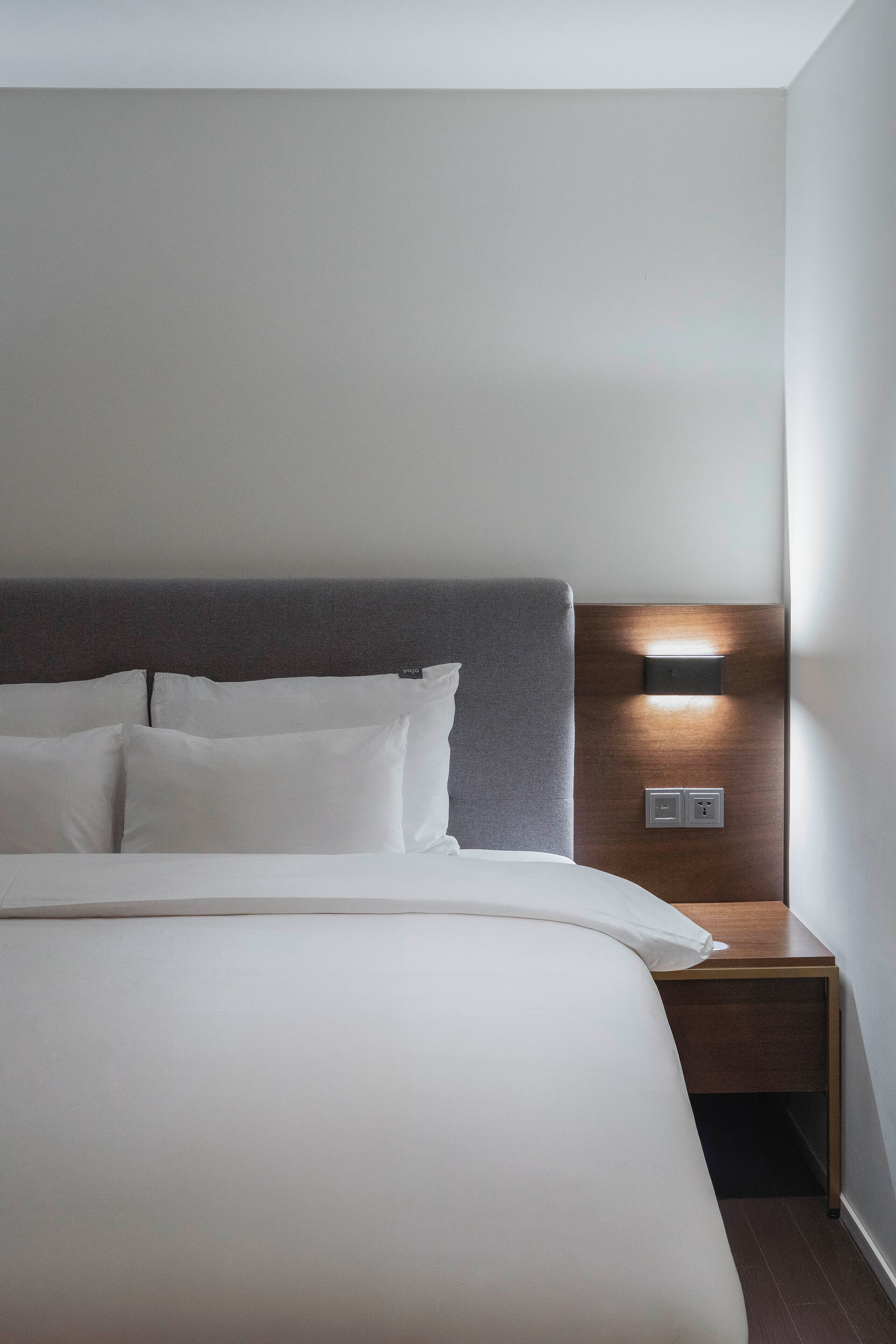 A neatly made bed with white linens and a dark headboard.