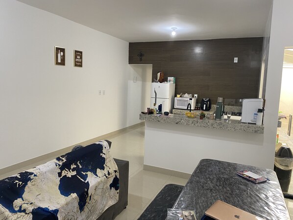 A modern kitchen with a refrigerator, microwave, and stove. There is a dining area with a table and a couch.