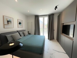 Un dormitorio moderno con una cama, un televisor de pantalla plana y obras de arte en las paredes.