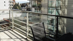A modern building with multiple balconies, large windows, and a glass railing.