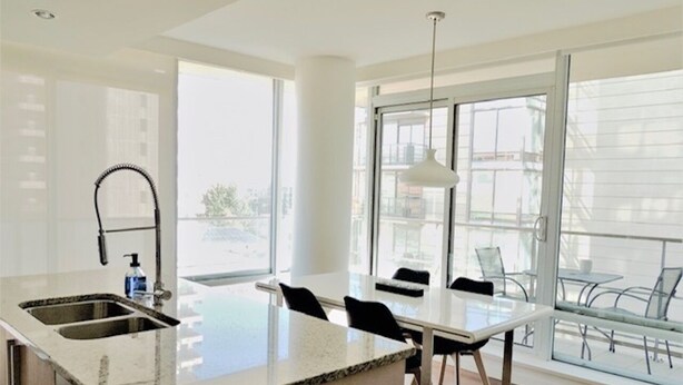 A modern kitchen with a large island, a dining area with chairs, and large windows offering a view of the city.