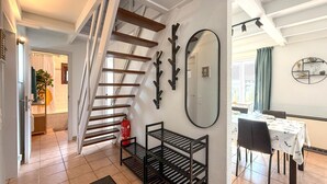 A staircase with wooden steps and metal railings, a dining area with a table and chairs, and a wall-mounted mirror. - 3 bedroom beautiful home in Bredene (Bredene)