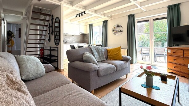A spacious living room with a grey sofa, a wooden coffee table, and a television on a wooden cabinet. - 3 bedroom beautiful home in Bredene (Bredene)