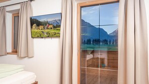 Una camera da letto con un letto, una finestra vista montagne e una porta scorrevole.