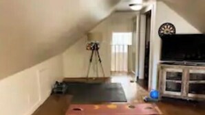 Une pièce avec un plancher en bois, des tapis de yoga, un trépied et un téléviseur.