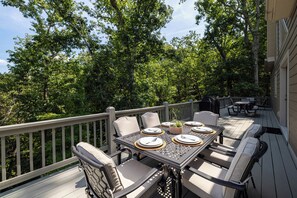 Eine Terrasse mit Tisch für vier Personen, umgeben von Stühlen, und einem Grill im Hintergrund.