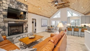 A spacious living area with a stone fireplace, leather sofa, and a dining area with a table and chairs.