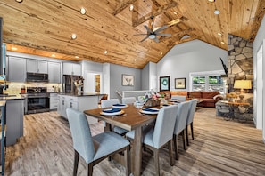 A spacious kitchen with modern appliances, a dining area with a wooden table and chairs, and a stone accent wall.