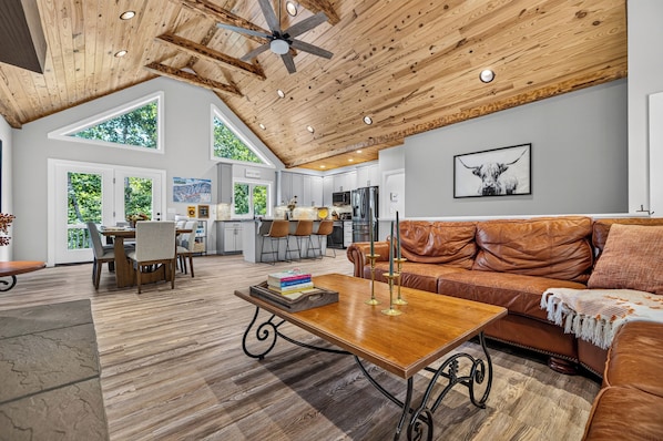 A spacious living area with a wooden ceiling, a leather sofa, and a dining table with chairs.