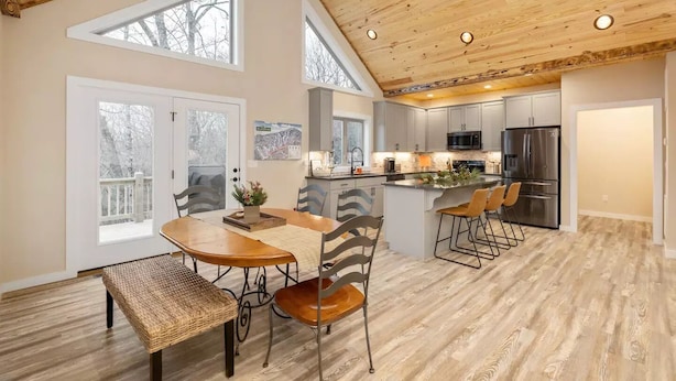 A spacious kitchen with modern appliances, a dining area with a wooden table and chairs, and large windows providing natural light.